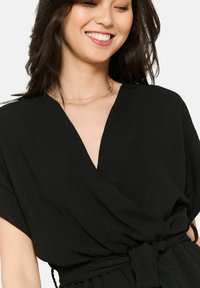 Czarny top o luźnym kroju z szerokimi krótkimi rękawami, z głębokim dekoltem w kształcie litery V i wiązaniem w talii, wykonany z teksturowanej, lekkiej tkaniny.
