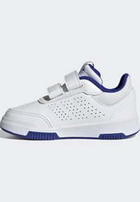Zapatilla blanca con acentos azules, fabricada en material sintético. Presenta dos tiras de Velcro y detalles perforados en el costado.