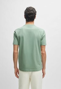 Korte mouwen, ronde hals t-shirt in lichtgroene katoen, met een gladde textuur en een ontspannen pasvorm, gecombineerd met crèmekleurige linnen broek.