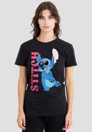 Black t-shirt featuring a cartoon design of a blue alien character, "Stitch," with bold pink text spelling "STITCH" beside it.