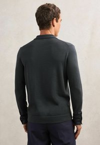 Dunkelgraues Polohemd mit langen Ärmeln, Rückansicht, mit weicher Textur, Kragen und Manschetten mit Knopfdetails.