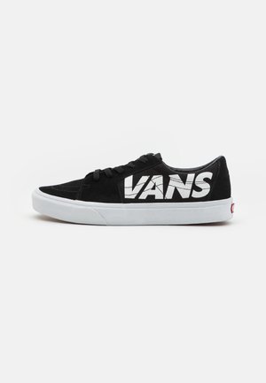 Czarny niskoprofilowy sneaker Vans z białą gumową podeszwą i dużym białym logo Vans po bokach, prezentowany na jednolitym białym tle.
