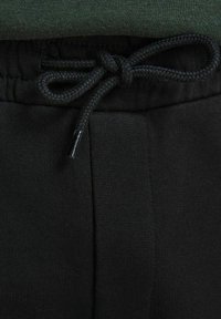 Zwarte sweatpants van stof met ribbeltextuur en een elastische tailleband. Voorzien van een trekkoord met een gevlochten ontwerp en een metalen aglet.