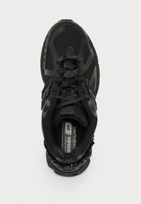 Black athletic shoe with mesh upper, lace closure, padded collar, and textured rubber sole. Features branding on the tongue and inner side.