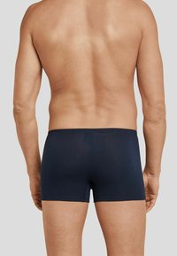 Dark blue boxer briefs made of smooth fabric, featuring a simple design with no visible patterns or hardware, covering lower back and hips.