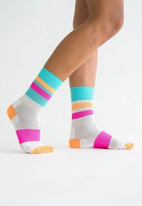Bunte Socken mit gestreiften Mustern in Türkis, Pink, Orange und Weiß. Hergestellt aus strukturiertem Stoff, knöchellang mit einer einfarbigen, orangen Zehenpartie.