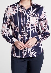 Marinblus med blommönster och kedjemönster, långa ärmar, knappstängning och kontrasterande vita ränder. Slätt tyg med skräddarsydd passform.