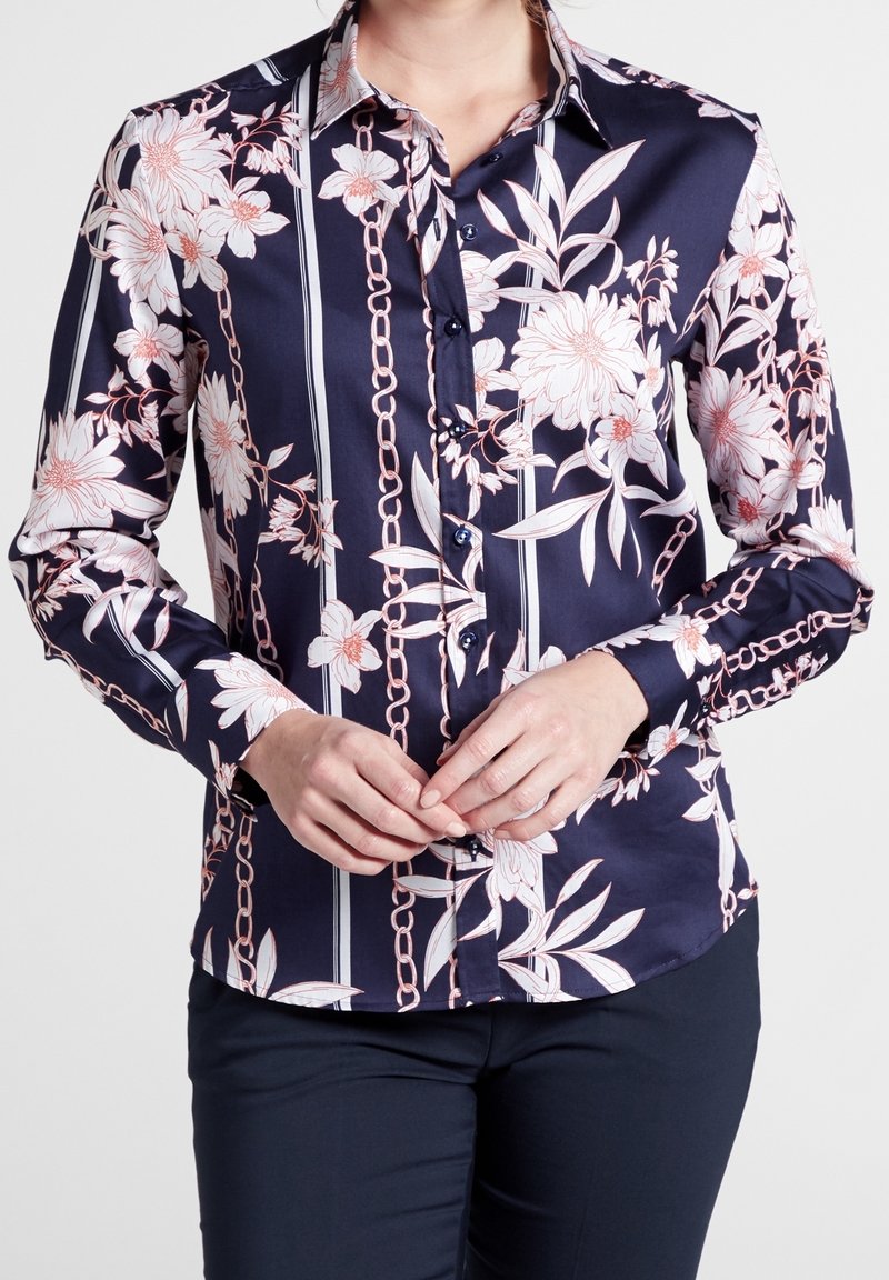 Marinblus med blommönster och kedjemönster, långa ärmar, knappstängning och kontrasterande vita ränder. Slätt tyg med skräddarsydd passform.