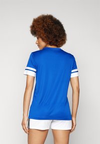 Camisola atlética azul com detalhes e riscas brancas nas mangas curtas. Feita de material liso e leve. Acompanhada de calções brancos.