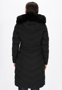 Sort puffermantel med vertikale chevron-syninger, udstyret med en kunstfærdig pelskrave og lange ærmer, designet til varme og dækning.