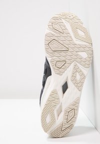 Sportovní bota s tmavým svrškem z prodyšné síťoviny a syntetických materiálů. Texturovaná světlá gumová podešev s geometrickými vzory pro trakci.