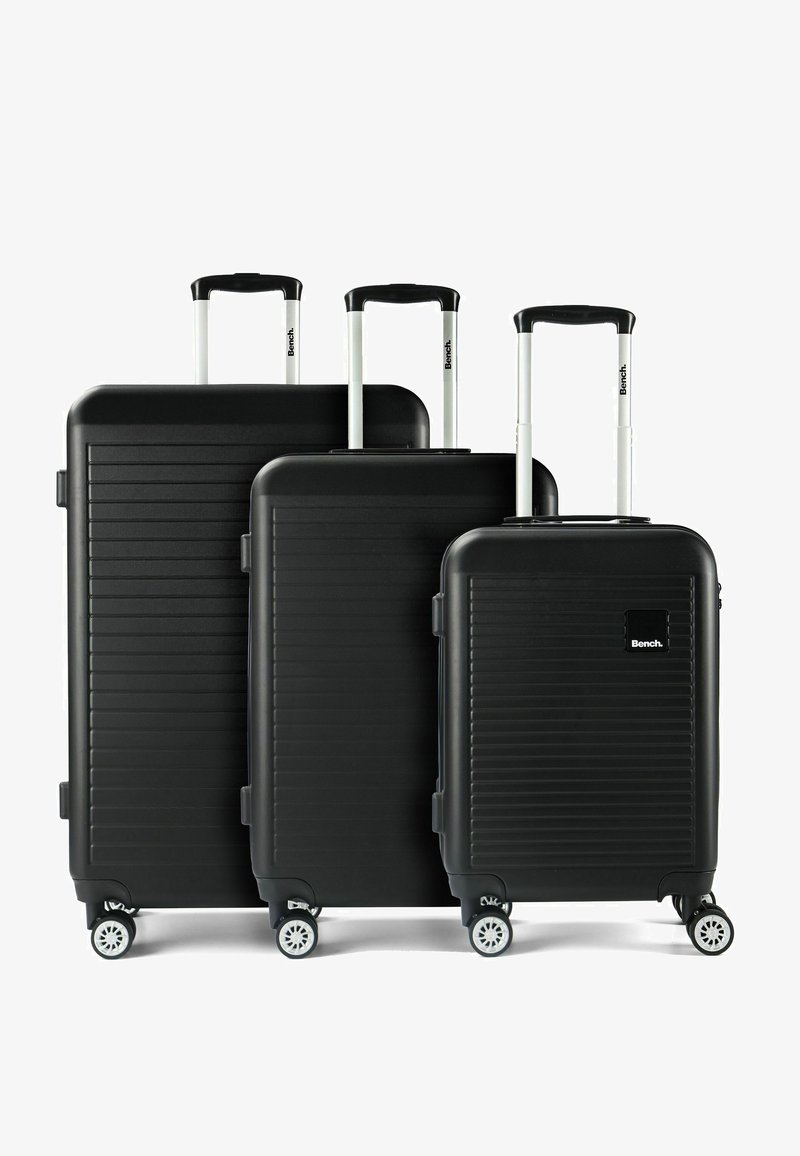 Tre valigie rigide nere di dimensioni piccola, media e grande, con manici telescopici e ciascuna dotata di quattro ruote bianche girevoli.