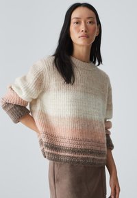 Wollpullover mit gerippter Textur in Pastelltönen, der von Creme über Rosa bis Braun an den Ärmeln und dem Saum verläuft. Kurze, lässige Passform.