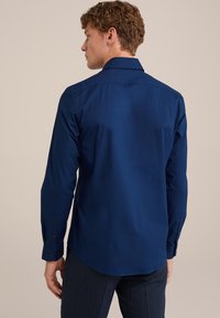 Camisa de manga larga azul marino con un cuello clásico, puños abotonados y una textura suave, exhibida desde la parte posterior.