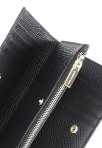 Czarny skórzany portfel z zamknięciem na zamek, złotymi akcentami, wieloma przegródkami na karty, teksturowanym wykończeniem oraz detalem logo na suwak.