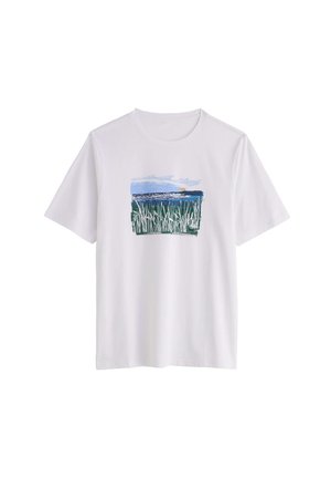 T-shirt bianca a maniche corte con un design stampato di canne verdi, acqua blu e cielo nuvoloso in una cornice rettangolare sul petto.