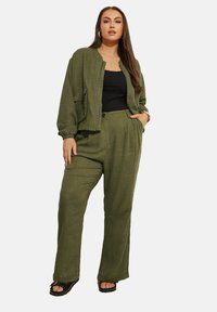 Olivgrön tvådelad outfit som består av en zip-up bomberjacka med en ficka och vida byxor. Lätt, texturerad tyg.