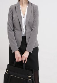 Gray tailored blazer over a white striped blouse, paired with a black pencil skirt and a structured black tote bag with gold accents.