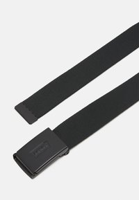 Cinturón de tela negra con una textura suave, que presenta una hebilla metálica rectangular grabada con un logo. Diseño simple, material duradero.