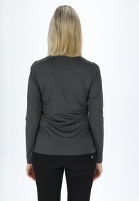 Langsleeve, fitted shirt van donkergrijs stof met een gladde textuur en platte naden, gedragen met zwarte broek. Geen opmerkelijke patronen of accenten.
