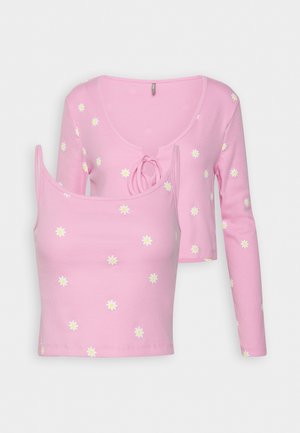 Ensemble deux pièces rose avec un top court à manches longues noué devant et un débardeur assorti, avec motif marguerites blanches et jaunes.