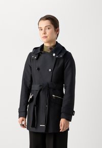 Zwarte dubbelbreasted trenchcoat met capuchon, ceintuur in de taille, ritszakken en manchetten. Glad materiaal met een matte afwerking.