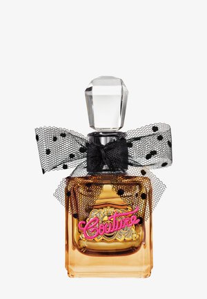 Amberkleurige glazen parfumfles met een kristallen stop, zwarte polkadot mesh strik en roze "Couture" opschrift op een sierlijk gouden etiket.