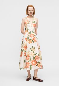 Φλοράλ φόρεμα με halter και βαθύ ντεκολτέ σε σχήμα V, με λευκό φόντο διακοσμημένο με πορτοκαλί και πράσινα λουλούδια. Μέσο μήκος, υφή λινό.