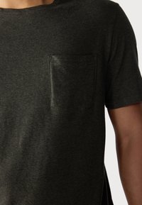 Dark green short-sleeve t-shirt made of textured cotton, featuring a single chest pocket and a crew neckline.