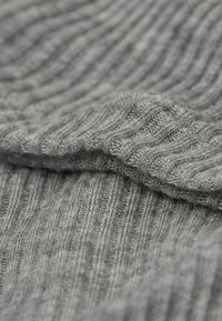 Tissu tricoté à côtes gris avec une texture douce, présentant des lignes horizontales distinctes et des plis, mettant en évidence son élasticité et la composition du matériau.