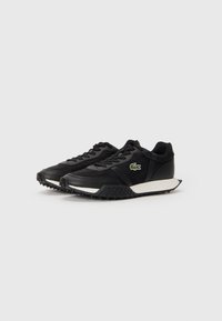 Black athletic sneakers made from leather and synthetic materials, featuring a textured sole, white midsole, and a small green logo accent on the side.