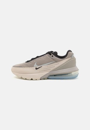 Baskets pour hommes Nike en mesh beige clair et gris avec une unité de coussin d'air visible, présentant un swoosh noir et des accents texturés.