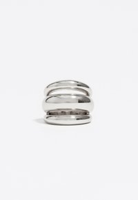 Anillo de metal plateado que presenta tres bandas apiladas con superficies lisas y brillantes y ligeros espacios entre cada banda. Forma redonda y acabado pulido.