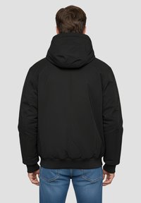 Schwarze Kapuzenjacke mit Reißverschluss, weicher Textur und elastischen Bündchen. Verfügt über einen körpernahen Saum, der ein glattes, stromlinienförmiges Design zeigt.