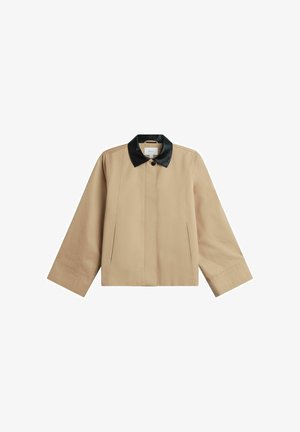 Beżowa kurtka z szerokimi rękawami i czarnym, skórzanym kołnierzem, pojedynczym guzikiem z przodu oraz ukrytym zapięciem na przodzie.