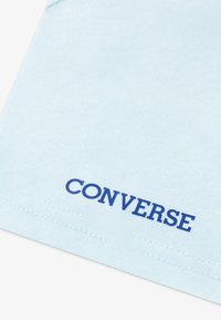 Ανοιχτό μπλε βαμβακερό μπλουζάκι με υφή υφάσματος και έντονο μπλε λογότυπο "CONVERSE" ραμμένο στο κάτω μέρος του τελειώματος.