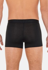 Black men’s boxer briefs with a textured waistband, fitted shape, and a smooth fabric, showcasing a minimalist design without patterns.