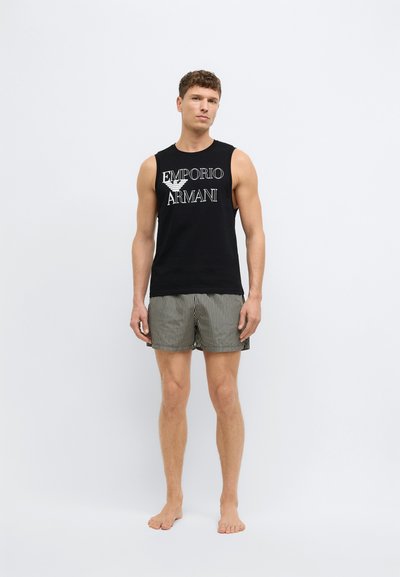 Μαύρο βαμβακερό αμάνικο τοπ με το λογότυπο «Emporio Armani»· σετ με πράσινα και λευκά ριγέ σορτς, ορατή υφή υφάσματος.