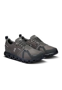 Baskets de sport grises avec une tige en maille texturée, semelle en caoutchouc noire et amorti flexible. Elles sont dotées de lacets et de boucles à l'arrière.