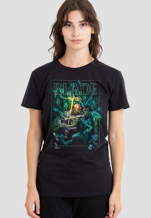 Young woman wearing black T-shirt with colorful graphic of a warrior fighting green monsters, with "BLADE" text above the scene.