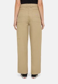 Beige wijde cargo broek met een hoge taille, achterzakken en een zijcargozak. Gladde textuur, duurzaam materiaal, gecombineerd met zwarte sneakers.