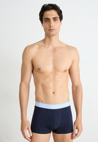 Marineblaue Boxershorts aus Baumwolle mit einem hellblauen elastischen Bund, der den Markennamen "GANT" in Wiederholung zeigt.