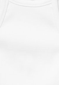 Débardeur blanc uni en tissu côtelé avec larges bretelles, mettant en valeur la partie supérieure de la poitrine et le décolleté.