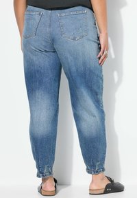 Jeans de mezclilla azul claro con un corte relajado y dobladillos enrollados, que cuentan con dos bolsillos traseros y un ligero desgaste para un aspecto usado.