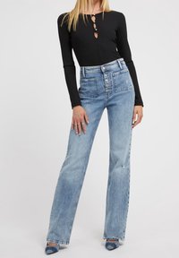 Zwarte lange mouwen bodysuit met knoopdetails, gecombineerd met lichtblauwe hoge taille denim jeans, met een rechte snit en subtiele vervaging.