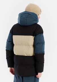 Daunenjacke mit einer blauen Kapuze, beigem Mittelteil und schwarzem unterem Abschnitt. Strukturierter Stoff mit einem gesteppten Design.
