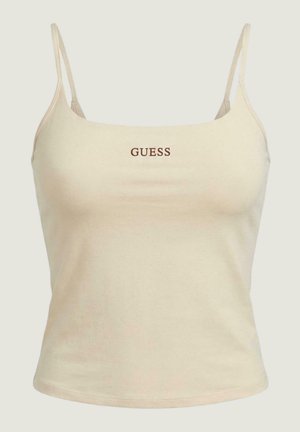 Top corto beige con spalline sottili e logo "GUESS" al centro in testo marrone sul davanti.