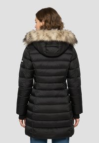 Schwarzer Steppmantel mit Kapuze, die mit Fell gefüttert ist, mit gestepptem Texturmuster, langen Ärmeln und einer taillierten Silhouette, die bis zur Mitte des Oberschenkels reicht.