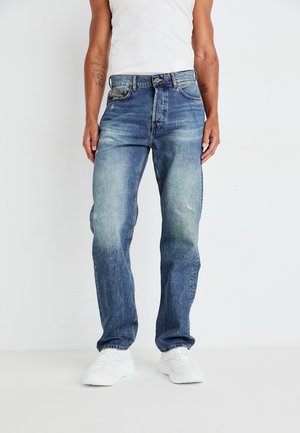 Blue denim jeans with a relaxed fit, featuring light wash fading, a button fly, five pockets, and white sneakers.