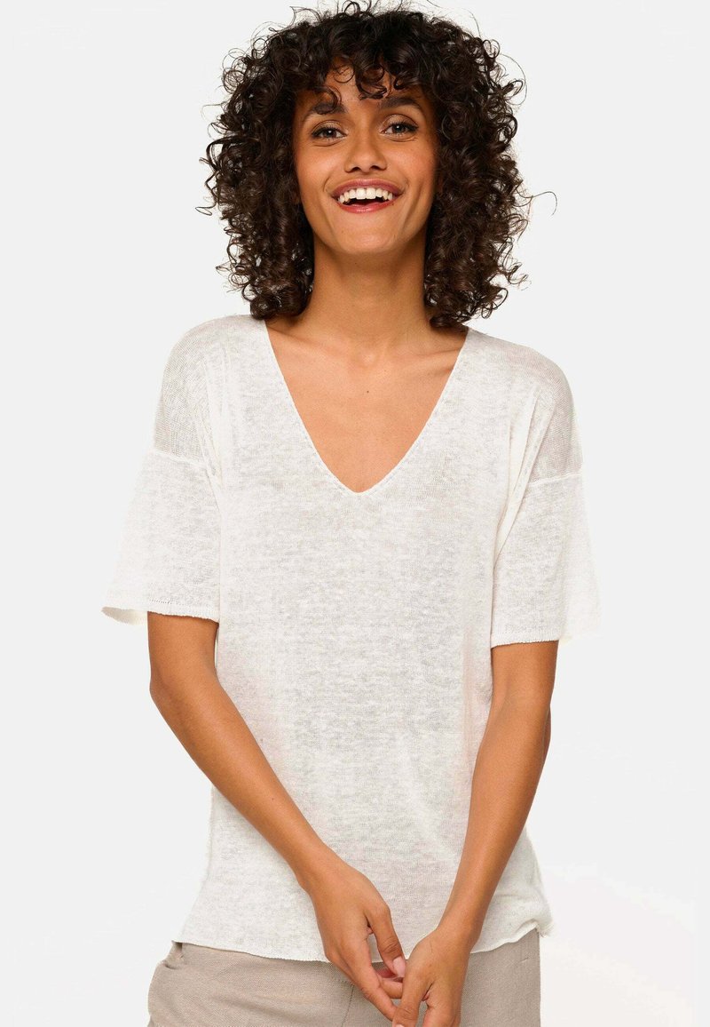Short-sleeve, v-neck top in lightweight, sheer white fabric with a relaxed fit and slightly frayed sleeve edges.